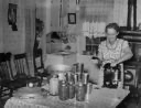 Image of Mrs. Christiansen of the Christiansen canning unit sealing cans. During 1939 she canned 2300 quarts which included 20 mutton, 2 deer, 2 beeves, 5 pigs. Fish was tried very successfully. In this cooperative agreement there were twenty-five users and outsid